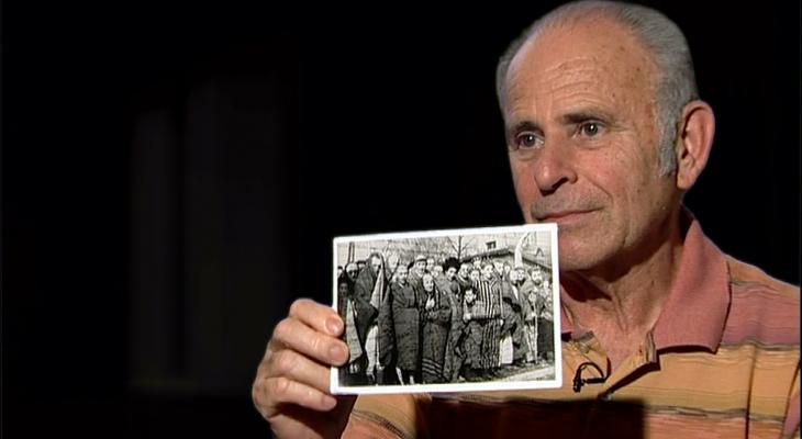 man holding up photo from concentration camp