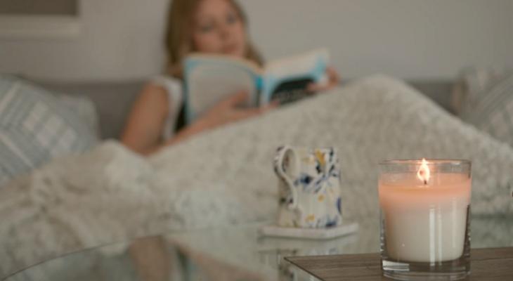 Woman reading a book with a candle on a table