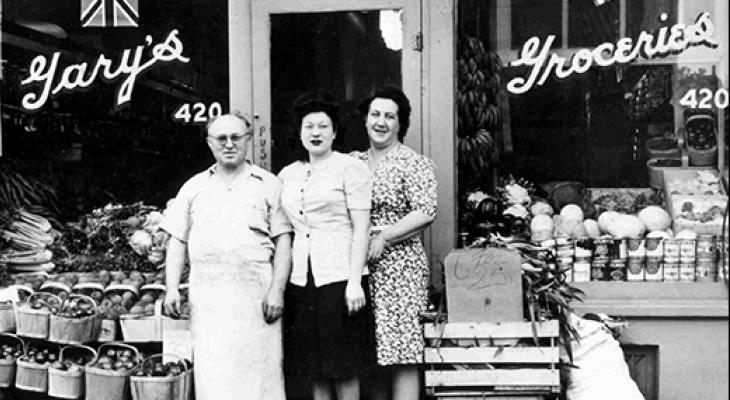 Three people stand in front of an old shop
