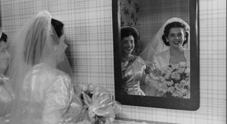 woman in wedding gown looking in mirror