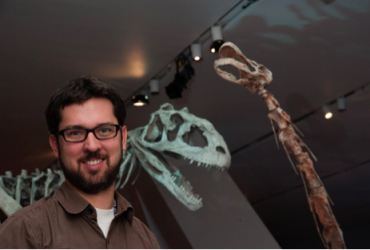 David Evans standing in front of dinosaur skeletons