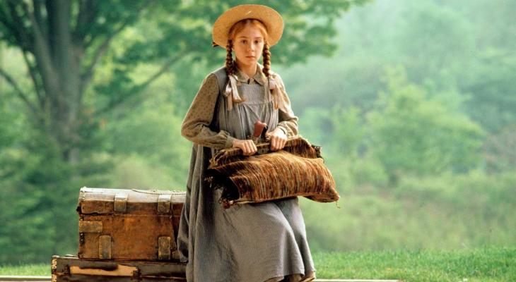 a young girl with braids and a wide brim hat sitting on a suitcase