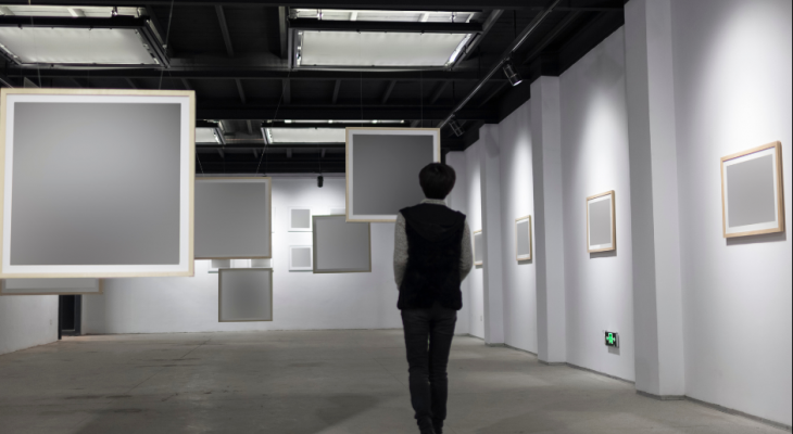 A person standing in a gallery, surrounded by empty canvases