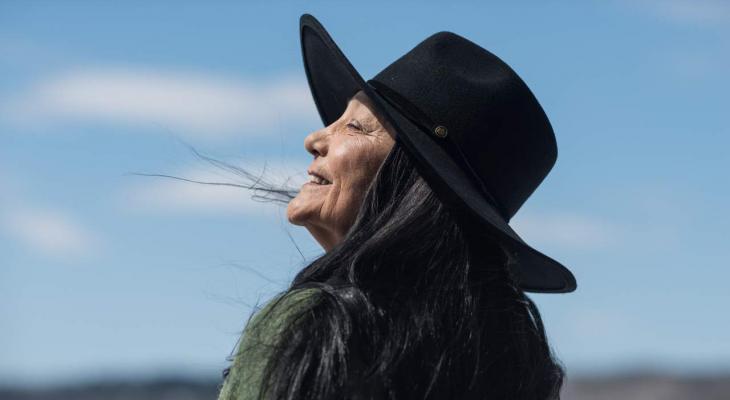 A woman faces the sun, smiling.