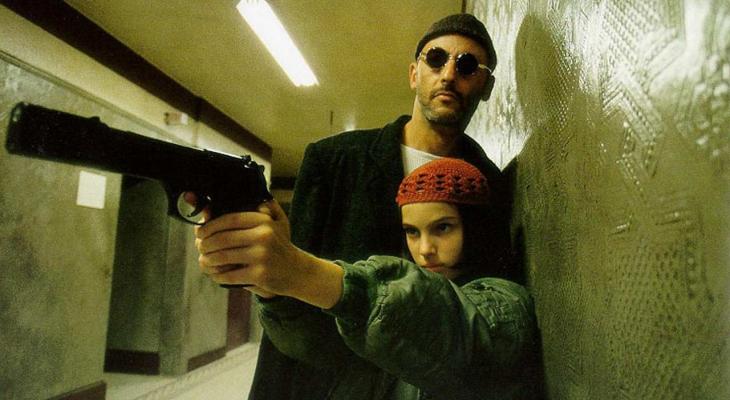 a man standing behind a young girl holding a gun