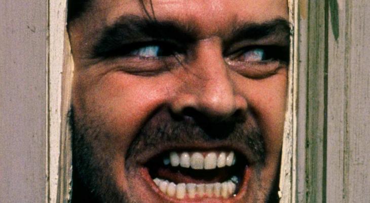Jack Torrance (Jack Nicholson) aggressively pushes his face through a broken door.