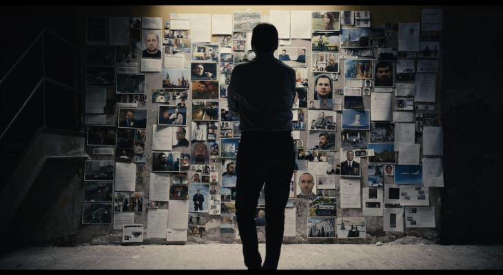 A man faces a wall of research materials.