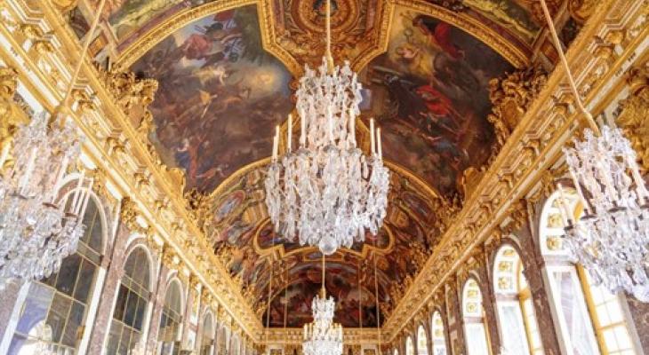 Hall of Mirrors at the Palace of Versailles during the day, featuring ornate painting ceiling, and grand chandeliers.
