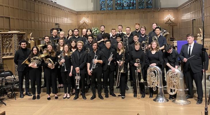 A group of brass musicians pose inside a church.
