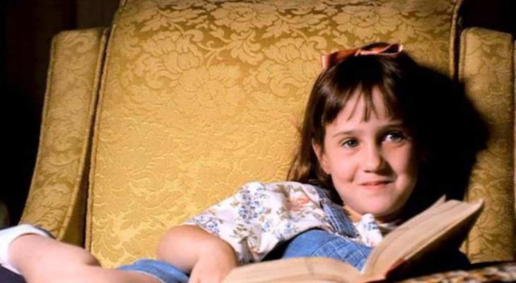 Matilda sits in an armchair reading a book.