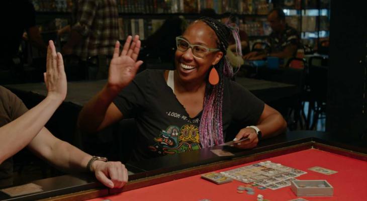 A woman high-fives a peer while playing a board game.