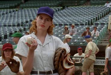 A woman holding a baseball and a baseball glove looks questioningly offscreen.
