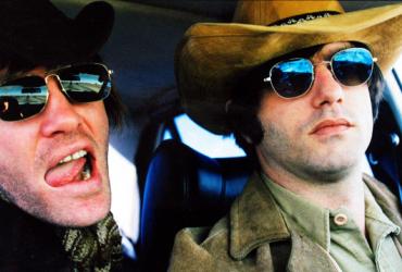 Two band members in sunglasses and cowboy hats gaze at the camera with rock'n'roll attitude.