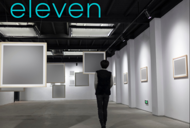A person standing in a gallery, surrounded by empty canvases