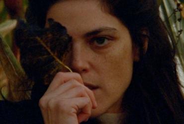 a woman holding a leaf over her left eye
