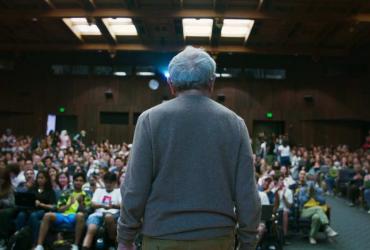 a man speaking to an auditorium full of students