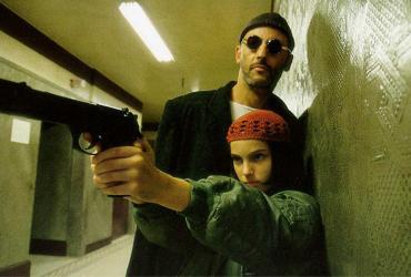 a man standing behind a young girl holding a gun