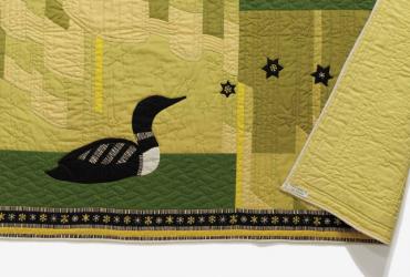 A green quilt with a black loon sewn on