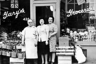 Three people stand in front of an old shop