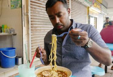 Suresh Doss eating a bowl of noodles at a restaurant