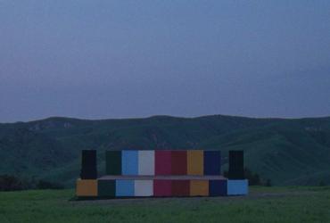a multi-coloured stage in the middle of a field with mountains in the background