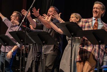 A group of people reach out towards the audience mid song