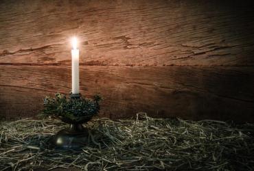 A candle lit on hay