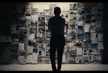A man faces a wall of research materials.