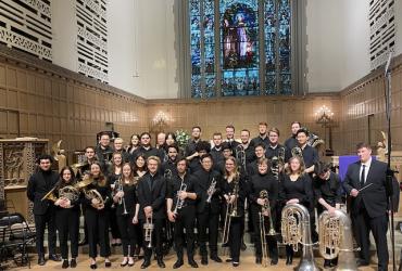A group of brass musicians pose inside a church.
