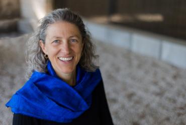 Gillian MacKay is smiling and looking ahead. She is wearing a deep blue scarf.