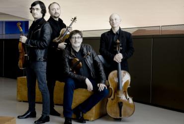 The four members of Quatuor Danel posing around a yellow sofa with their strings.