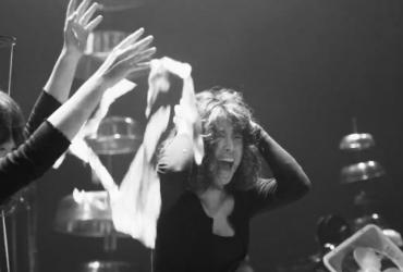 This is a black and white picture, and the person in the picture is raising both hands, immersed in the music.