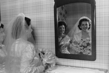 woman in wedding gown looking in mirror