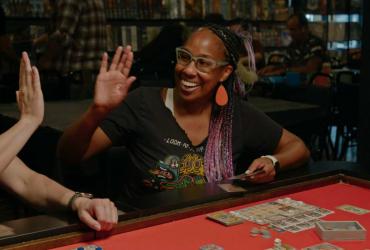 A woman high-fives a peer while playing a board game.